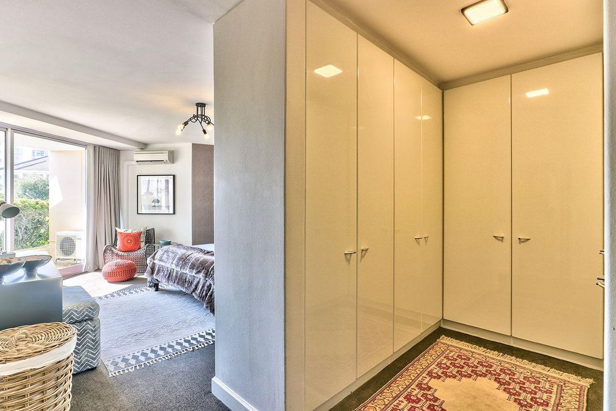 Spacious bedroom featuring extensive built-in cupboards, neutral finishes, and a sliding glass door providing access to an outdoor balcony area.