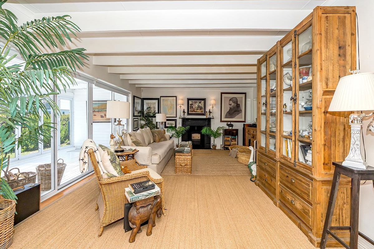 Spacious living room featuring exposed ceiling beams, a classic fireplace, and large sliding glass doors providing seamless access to the outdoor patio area.