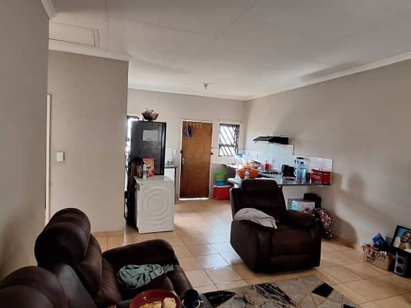 Open-plan living area featuring tiled flooring and a functional kitchen space with built-in cabinetry and an extractor fan.
