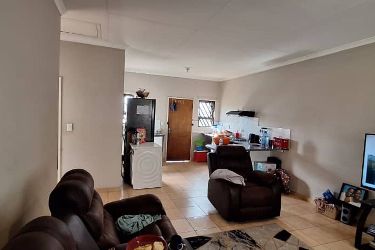 Open-plan living area featuring tiled flooring and a functional kitchen space with built-in cabinetry and an extractor fan.
