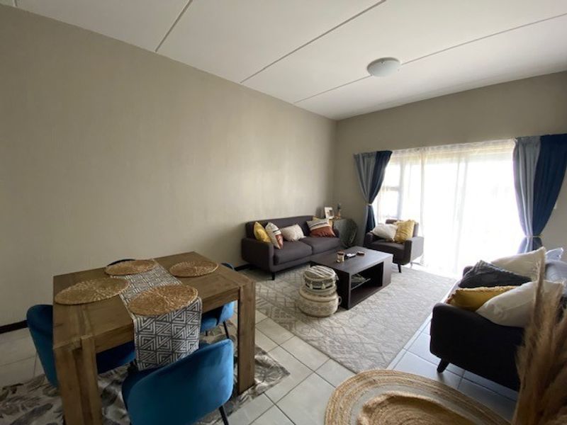 An open-plan living and dining area featuring tiled flooring and a large sliding glass door providing natural light.