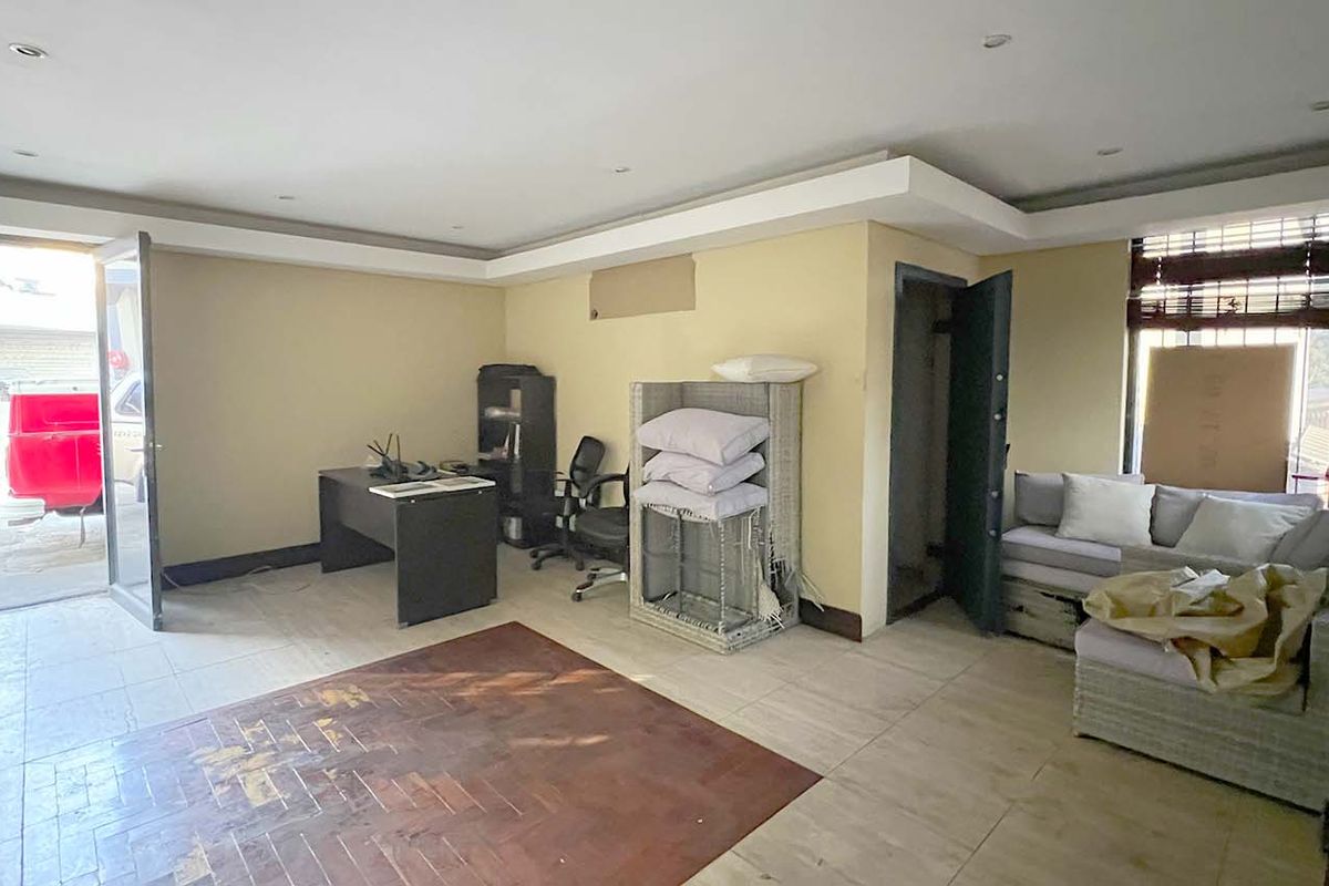 A functional office space featuring a mix of parquet and tiled flooring, recessed ceiling lights, and direct access to the exterior.