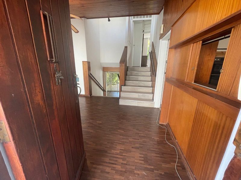 Entrance foyer featuring parquet flooring, timber wall paneling, and a staircase leading to the upper level.