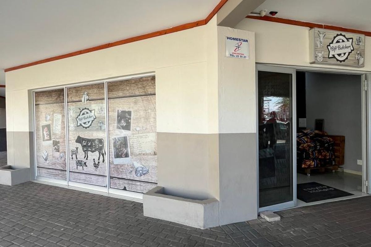 Front entrance of a commercial business unit featuring a paved walkway, covered porch area, and glass storefront display.