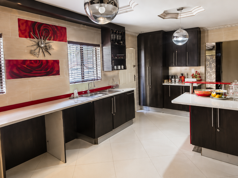 Modern kitchen featuring dark wood cabinetry, stone countertops, integrated appliances, and tiled flooring with ample workspace and natural light.