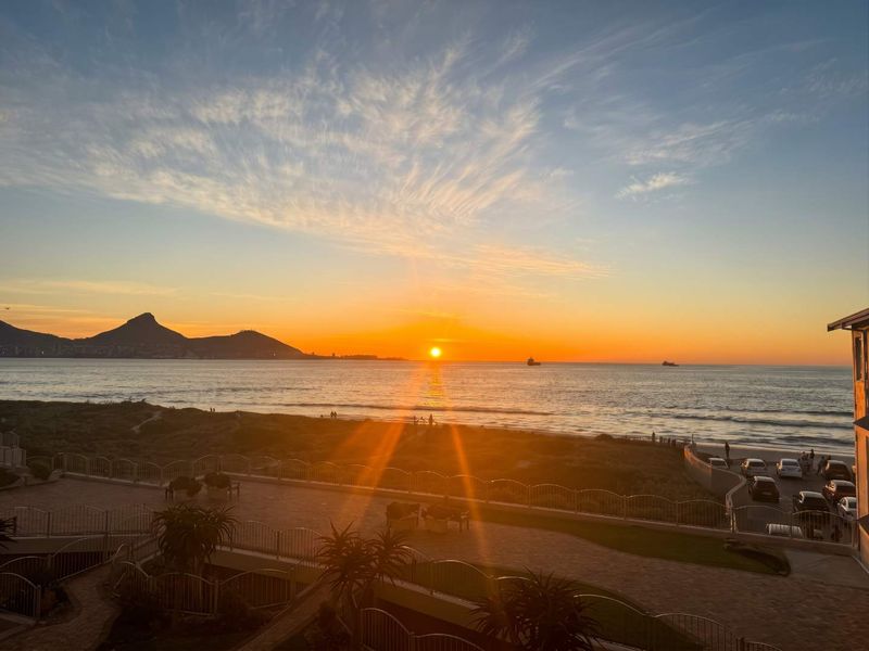 Stunning sunset view overlooking the ocean, beach, and coastal landscape from an elevated apartment position.
