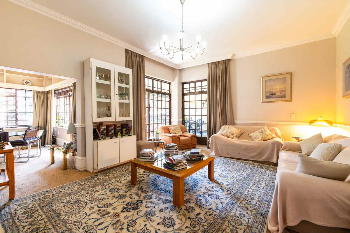 Spacious living room featuring classic crown molding, chair rail detailing, a built-in display cabinet, and large multi-pane windows with access to the patio.