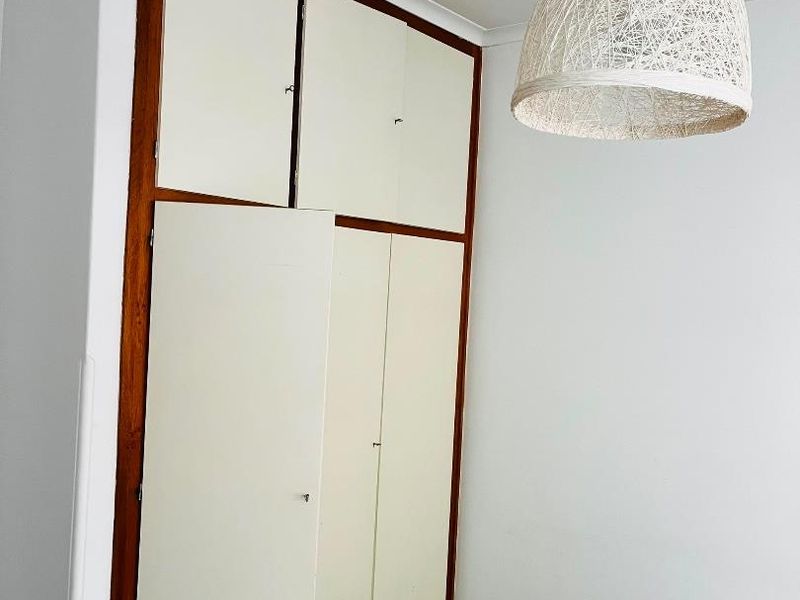 A bedroom featuring built-in cupboards with wooden frames and white doors, finished with coving and carpeted flooring.