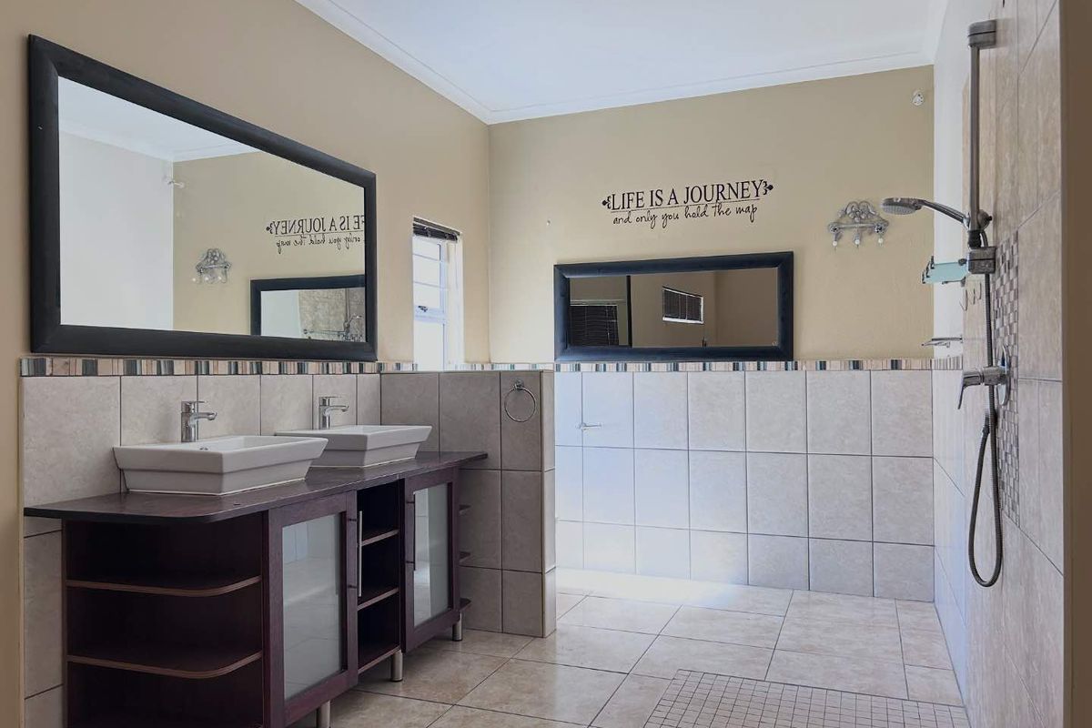 Spacious bathroom featuring a double vanity with vessel sinks, a large walk-in shower with tiled walls, and neutral floor tiling.