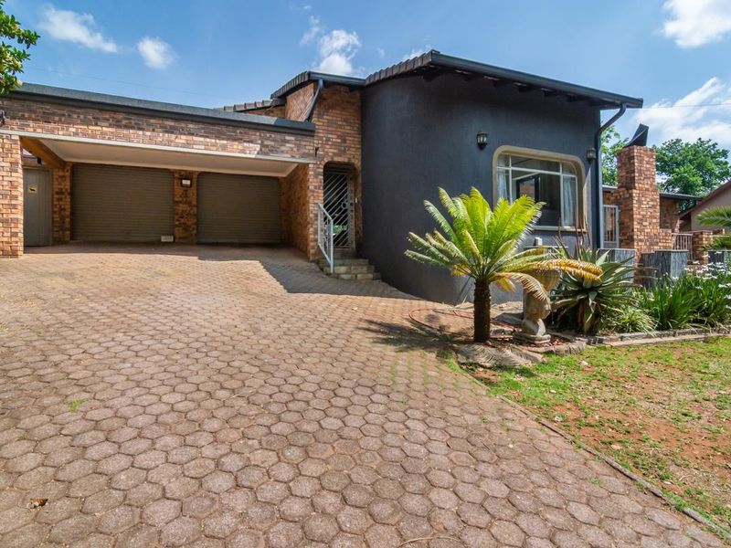Front view of a residential property featuring a double garage, paved driveway, and a combination of brick and painted exterior finishes.