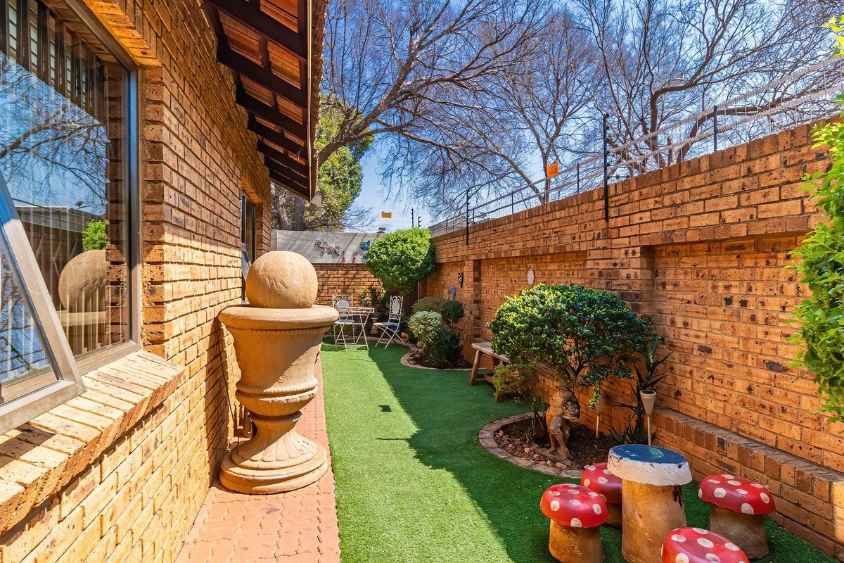 A private rear garden area featuring face brick walls, artificial lawn, and secure perimeter fencing, providing a low-maintenance outdoor space.