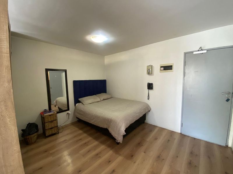 A functional bedroom featuring laminate flooring, a flush mount ceiling light, and integrated intercom and electrical distribution systems.