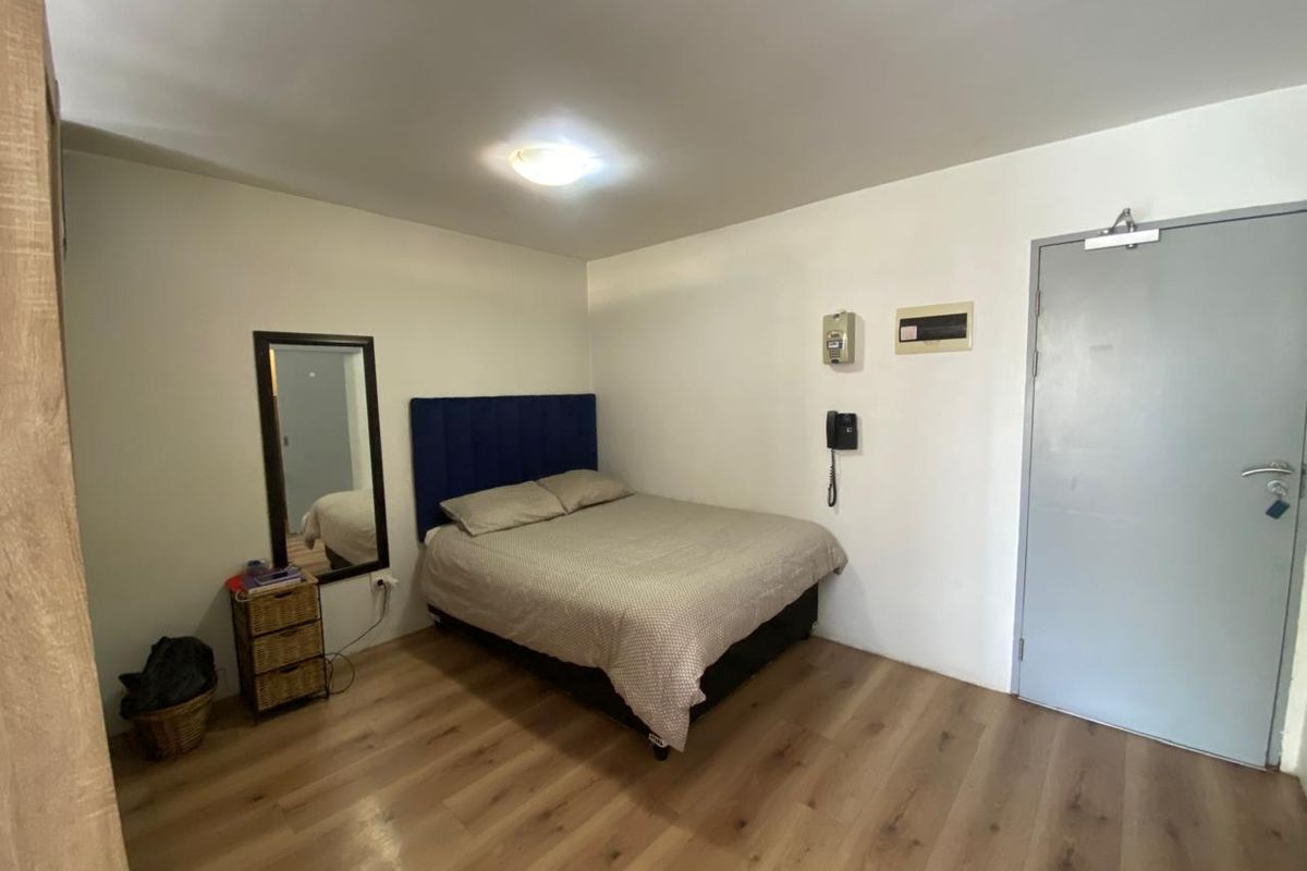 A functional bedroom featuring laminate flooring, a flush mount ceiling light, and integrated intercom and electrical distribution systems.