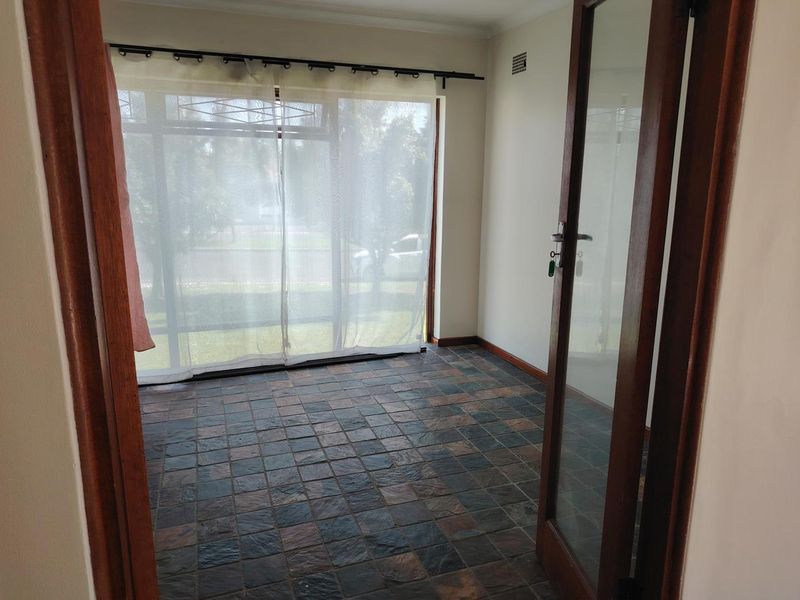 An empty living area featuring slate tile flooring and a large glass sliding door providing natural light and garden views.