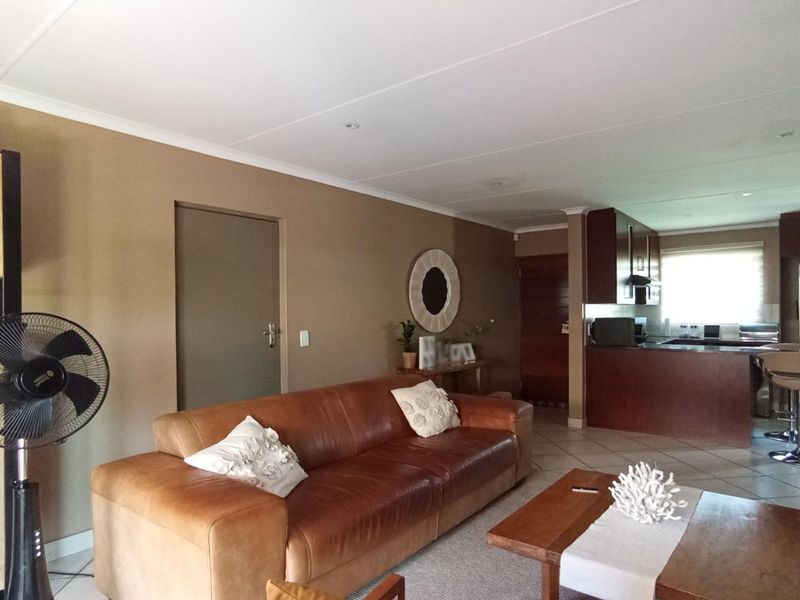 Open-plan living area featuring tiled floors and a functional kitchen with built-in cabinetry and a breakfast peninsula.