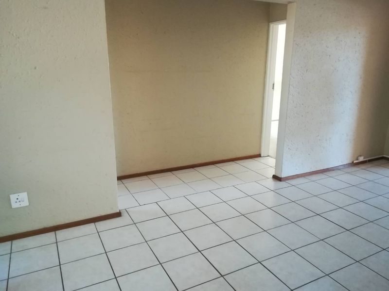 An empty living area featuring neutral ceramic floor tiles and textured walls, providing a blank canvas for interior design.