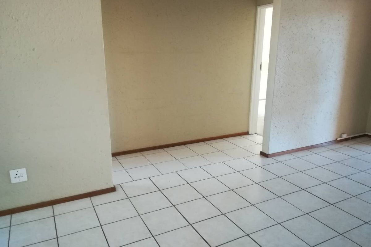 An empty living area featuring neutral ceramic floor tiles and textured walls, providing a blank canvas for interior design.