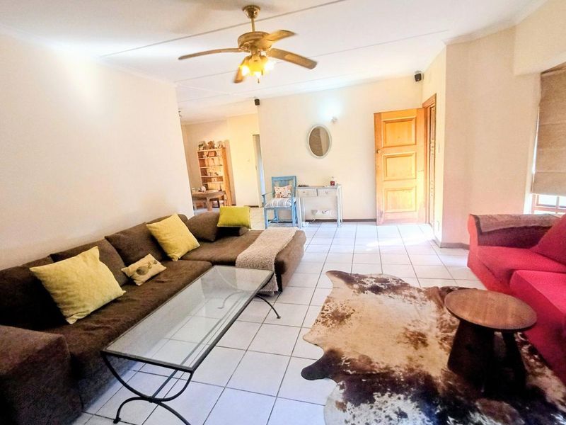 Spacious living area featuring tiled flooring, a ceiling fan, and a solid timber door, offering a functional layout for comfortable family living.
