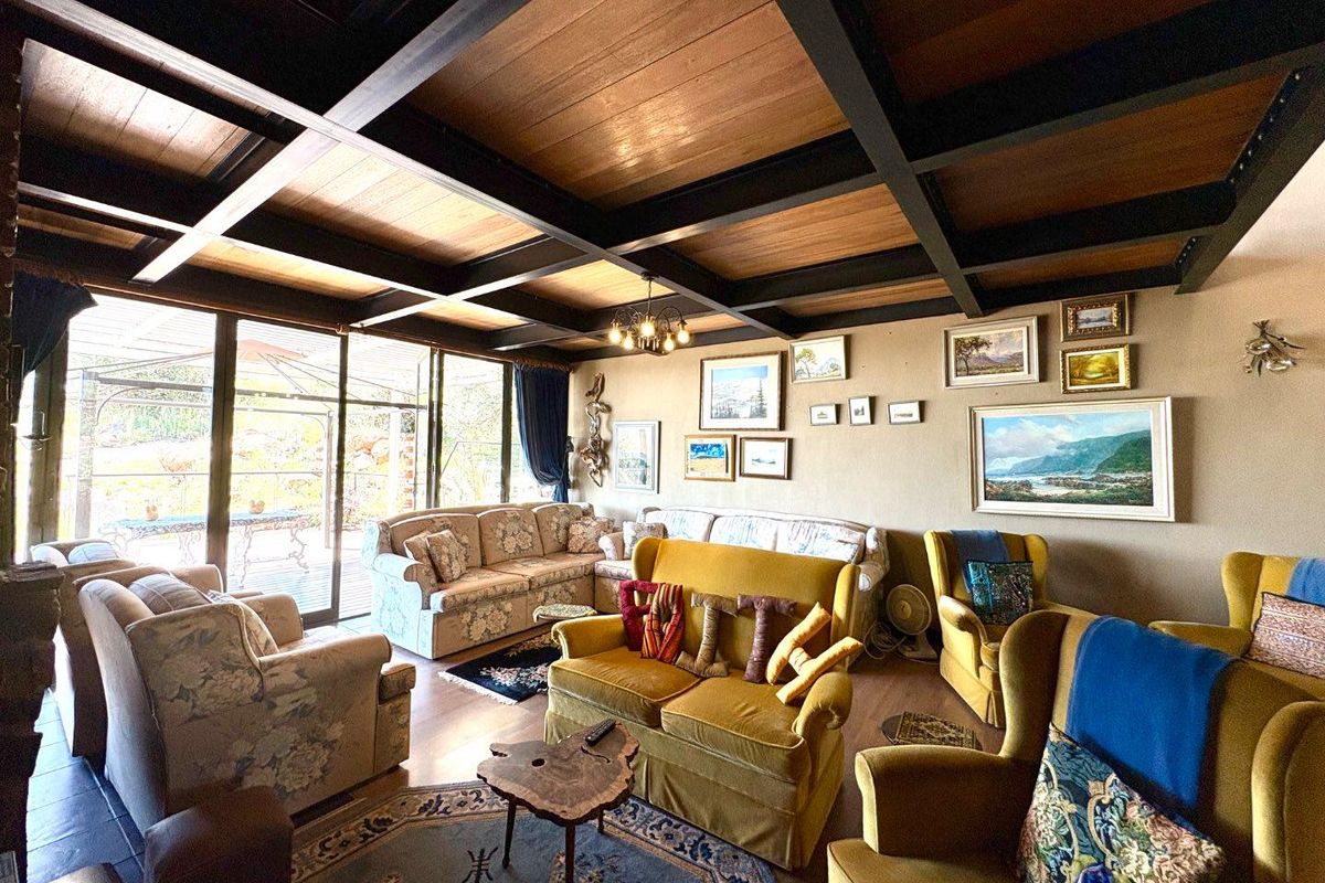 Spacious living room featuring a distinctive exposed timber beam ceiling, large glass sliding doors providing natural light, and direct access to the outdoor patio area.