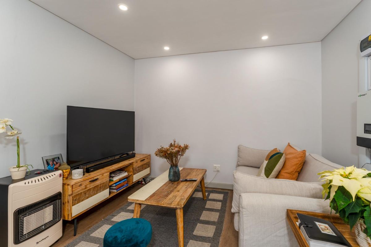 A well-maintained living room featuring recessed downlighting and a wall-mounted inverter system, providing a clean and functional space.