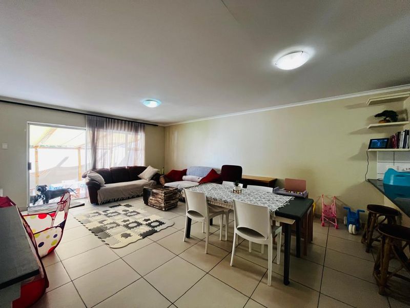 Spacious open-plan living and dining area featuring neutral tiled flooring and large sliding glass doors providing access to the outdoor patio.