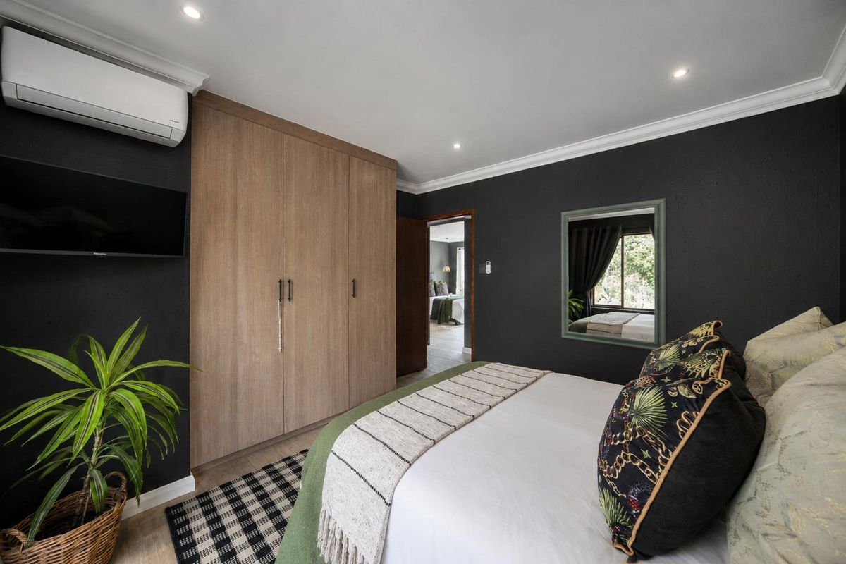 A well-maintained bedroom featuring dark accent walls, built-in wooden cabinetry, and a split-system air conditioning unit.