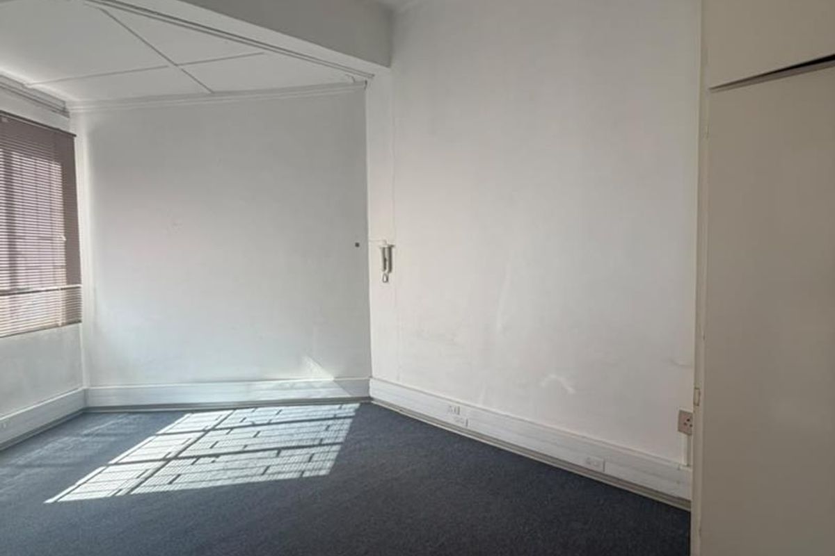 An empty bedroom featuring built-in cupboards, carpet flooring, and natural light through venetian blinds, offering a blank canvas for renovation.