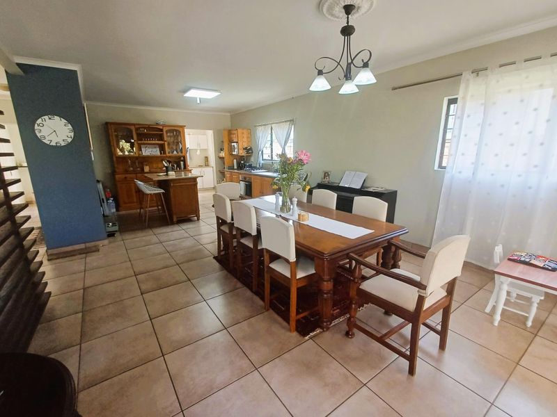 Spacious open-plan dining area featuring tiled flooring, decorative ceiling rose, and direct access to the kitchen and scullery.