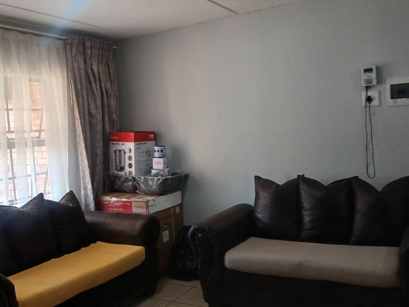 A living room area featuring tiled flooring, an intercom system, and a wall-mounted electrical distribution board.