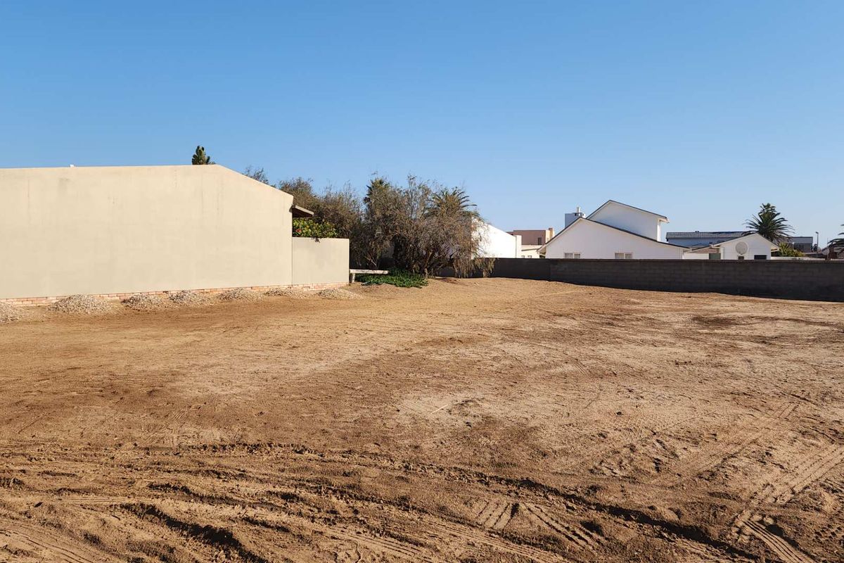 A vacant residential plot of land featuring perimeter boundary walls and level, cleared ground ready for development.