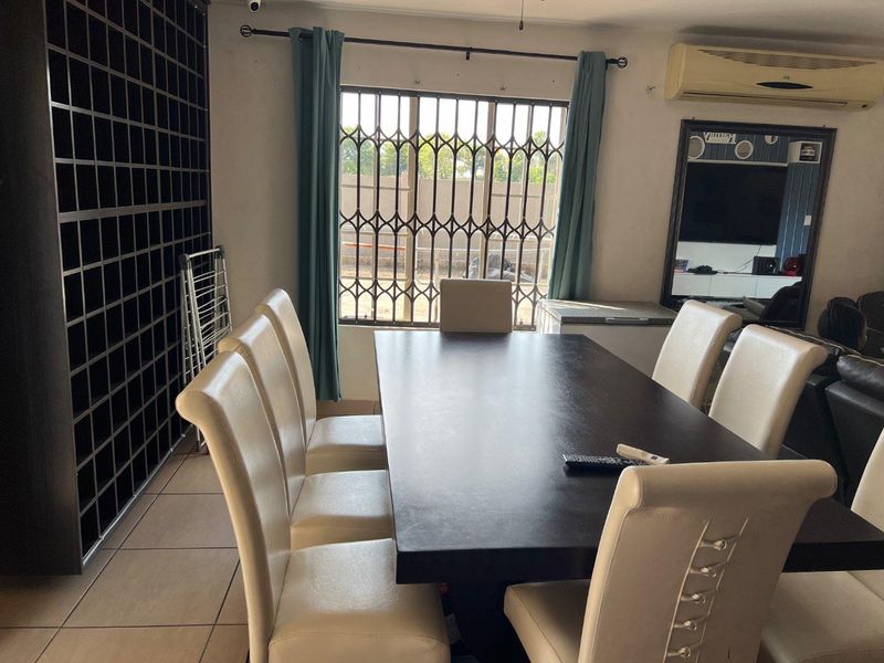 Dining area featuring tiled flooring, a large built-in shelving unit, and security bars on the window.