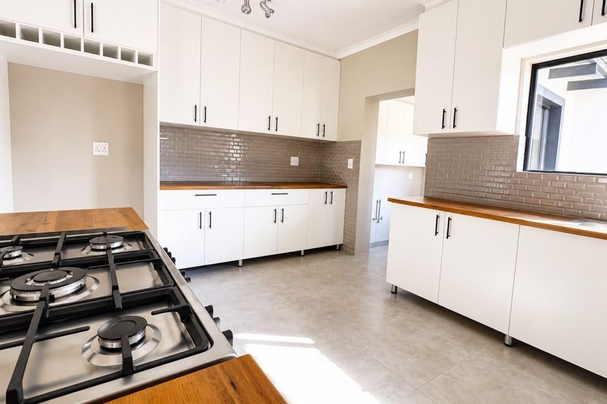 Modern kitchen featuring white cabinetry, wooden countertops, a gas hob, and a subway tile backsplash, offering a clean and functional workspace.