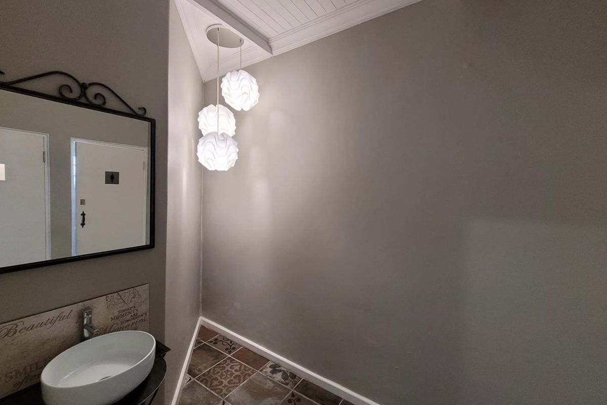 A compact bathroom featuring a modern vessel sink, decorative patterned floor tiles, and contemporary pendant lighting.