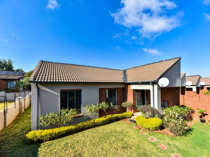 Front elevation of a well-maintained townhouse featuring a tiled roof, brick and plaster facade, and a landscaped front garden with a covered entrance.