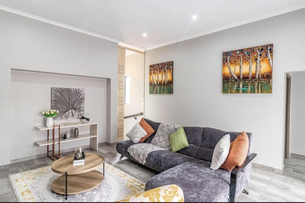 A bright and modern living room featuring neutral wall tones, recessed downlighting, and durable tiled flooring, creating a clean and inviting atmosphere.