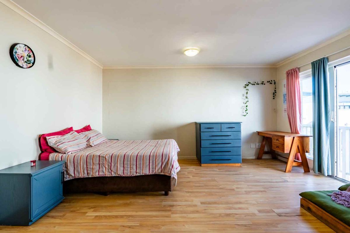Spacious bedroom featuring light wood-look laminate flooring and a large sliding glass door providing access to an outdoor area.