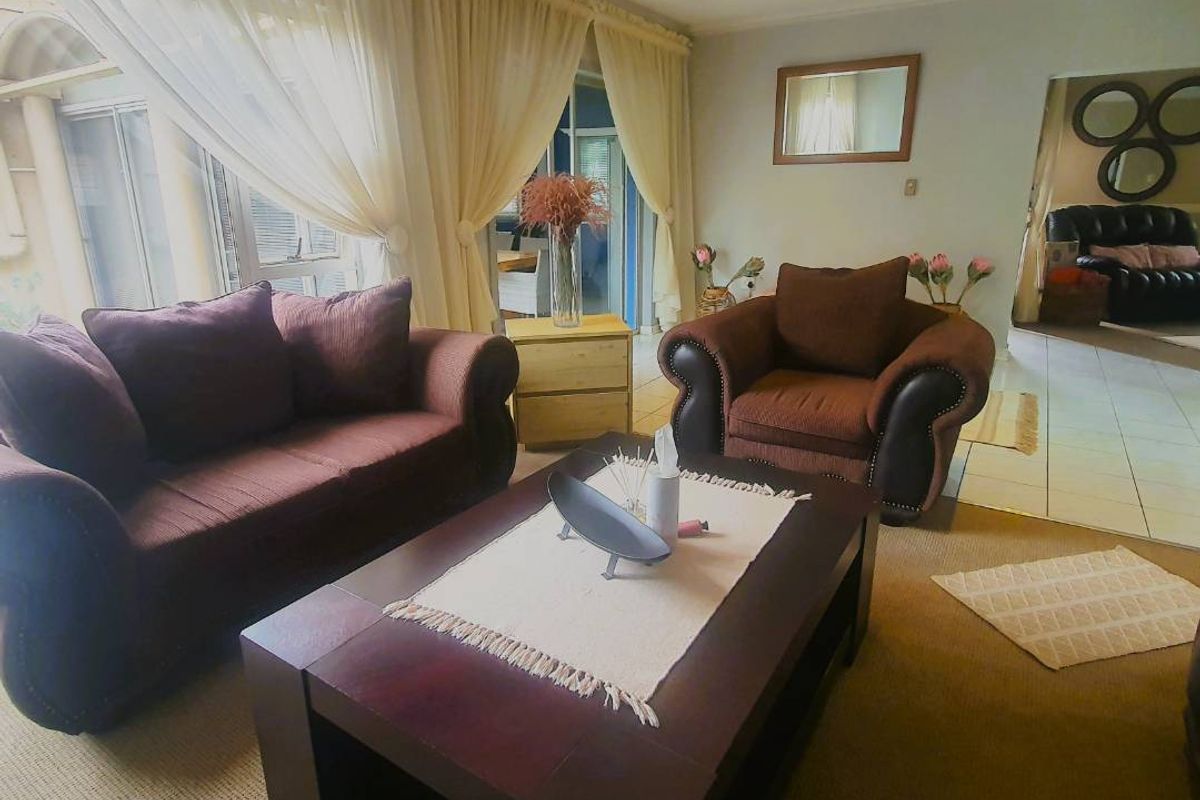 A comfortable living room featuring recessed lighting, carpeted floors, and large sliding glass doors that provide access to the outdoor area.