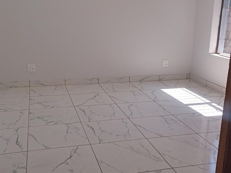 A bright, empty bedroom featuring modern marble-look ceramic floor tiles and clean white walls, ready for personalization.