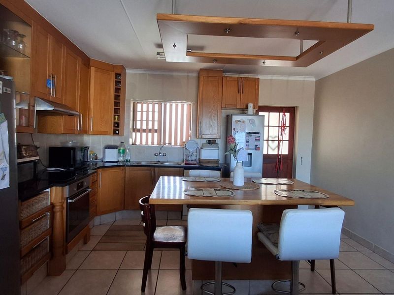 A functional kitchen featuring wooden cabinetry, built-in appliances, a central island with seating, and tiled flooring.