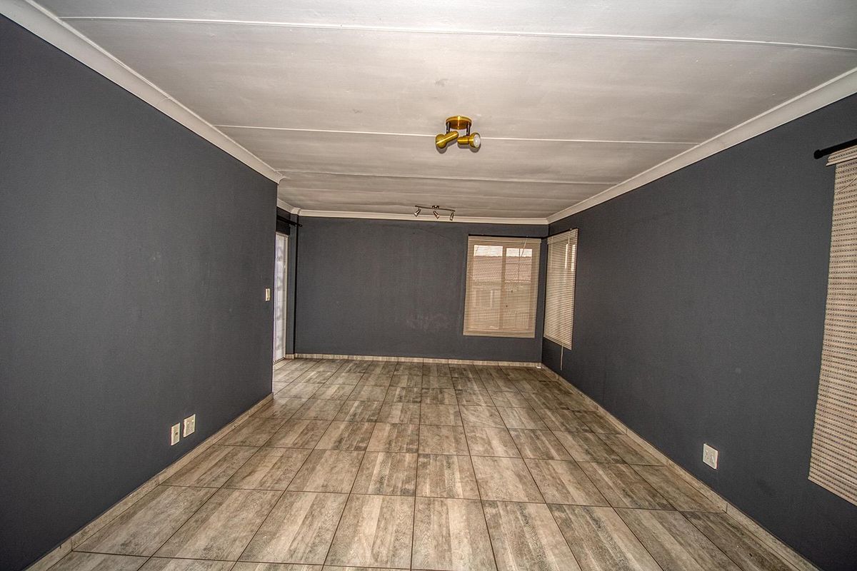 An empty living room featuring dark grey painted walls, wood-look ceramic floor tiles, and modern spotlight fixtures.