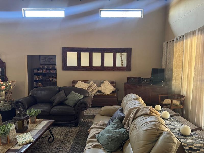 A spacious living room featuring high ceilings with clerestory windows, providing natural light and a built-in recessed shelving area.