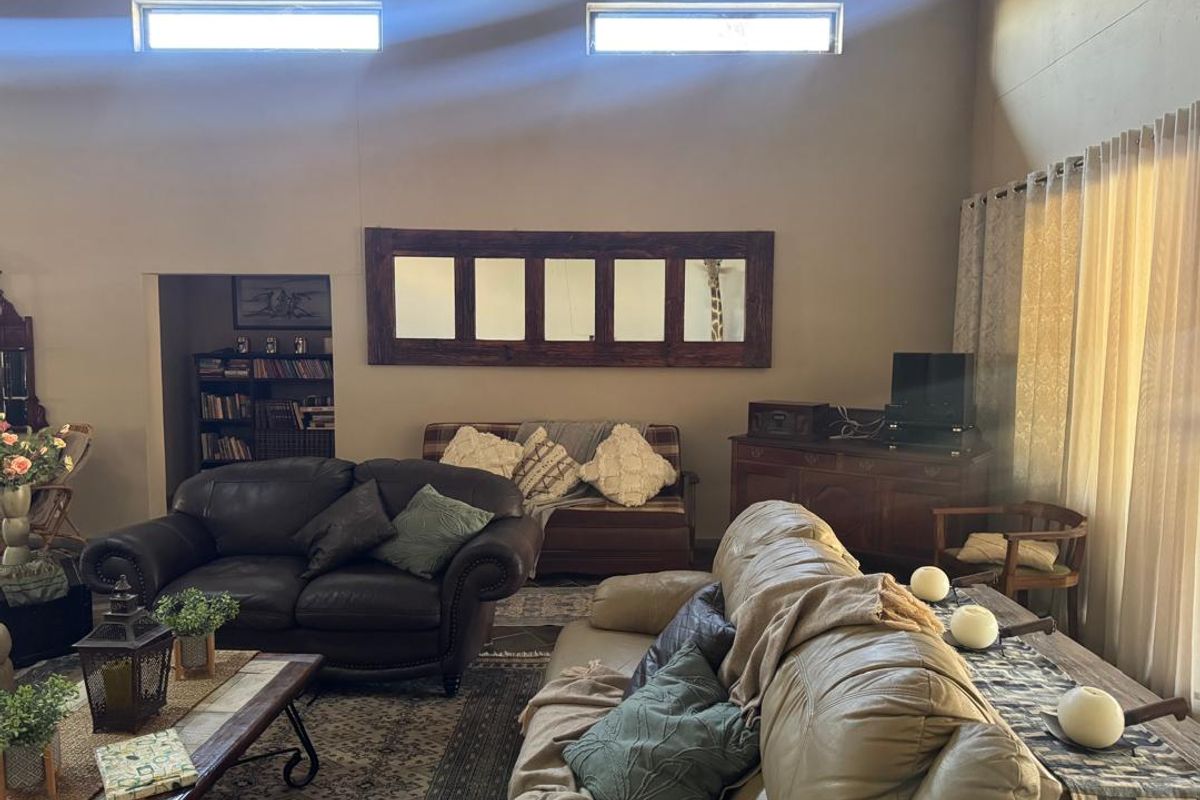A spacious living room featuring high ceilings with clerestory windows, providing natural light and a built-in recessed shelving area.