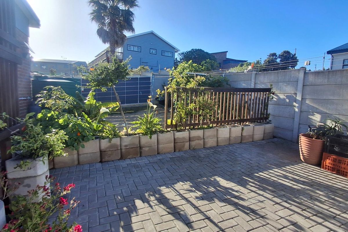 A rear courtyard area featuring paved flooring, a timber fence, and a precast concrete boundary wall.