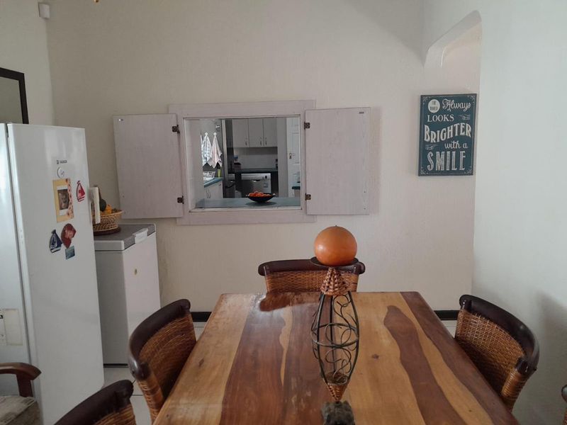 Dining area featuring a functional serving hatch connecting to the kitchen, with neutral wall finishes and tiled flooring.