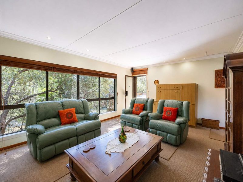 A comfortable living room featuring large windows with natural views, recessed lighting, and neutral carpeting, offering a bright and inviting space.