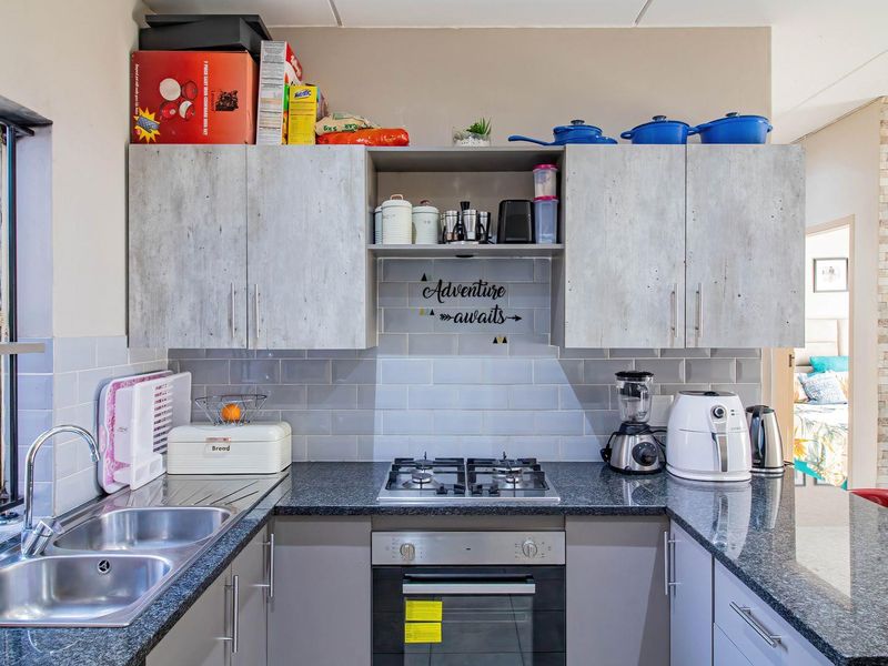 Modern kitchen featuring granite countertops, subway tile backsplash, built-in gas hob, oven, and ample cabinetry for storage.
