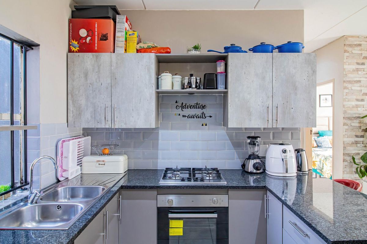 Modern kitchen featuring granite countertops, subway tile backsplash, built-in gas hob, oven, and ample cabinetry for storage.