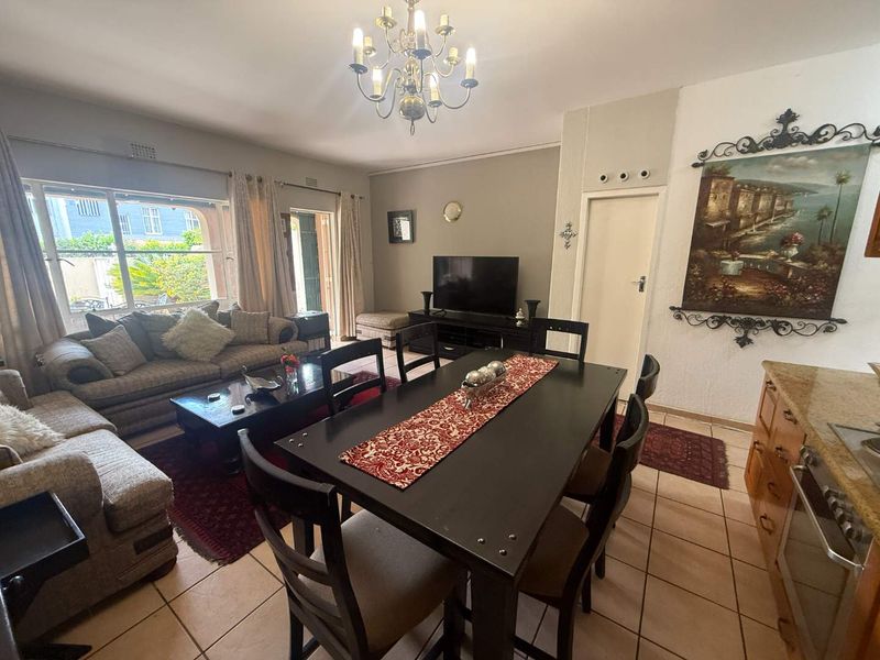 Open-plan living and dining area featuring tiled flooring, a central chandelier, and direct access to the outdoor patio through sliding glass doors.