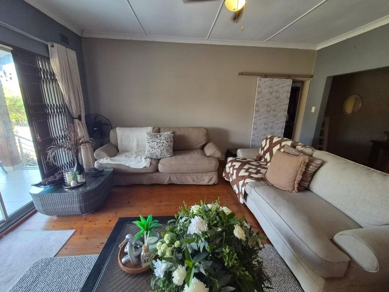 A living room featuring timber flooring, a ceiling fan, and a sliding glass door leading to an outdoor area.
