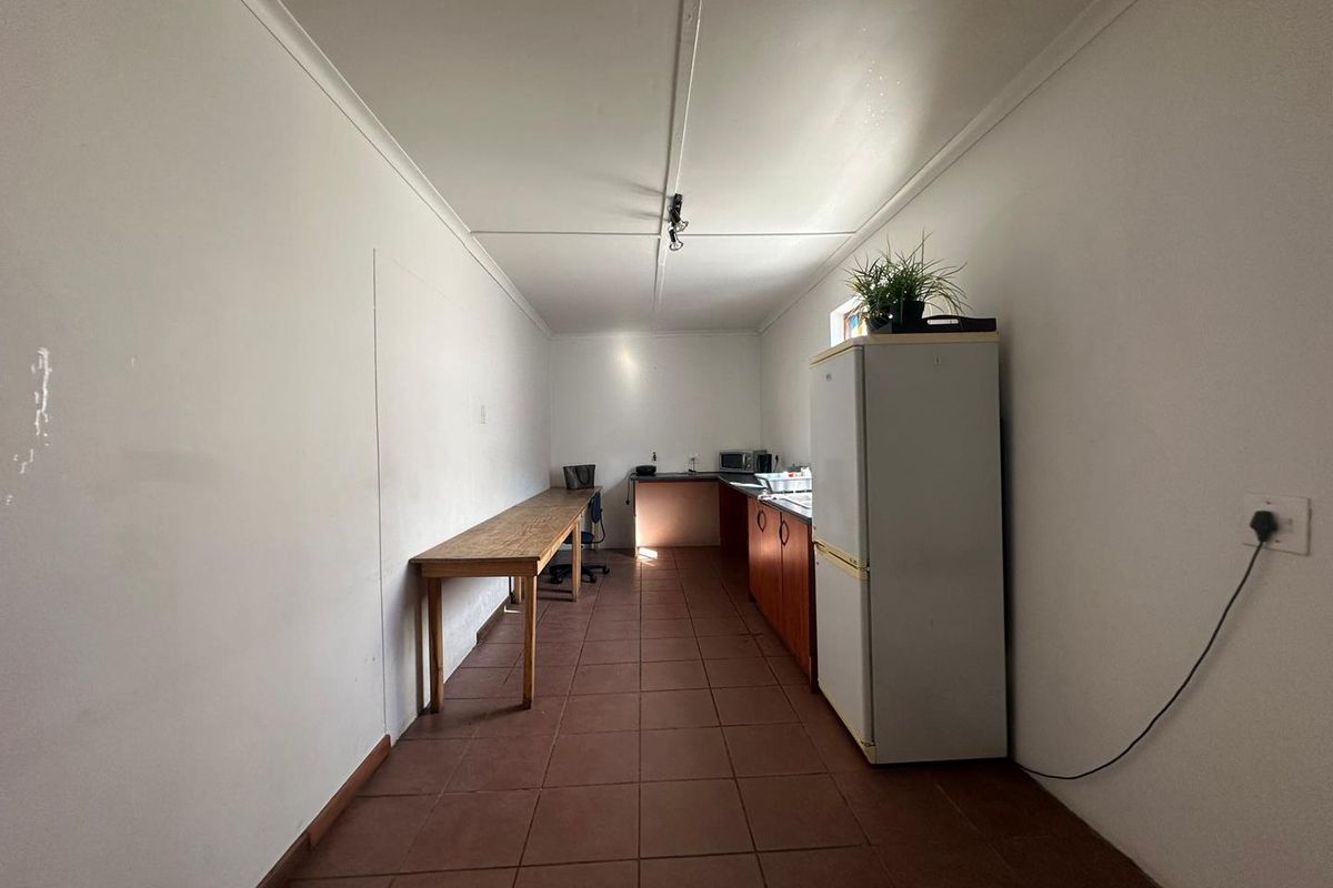 A functional office kitchenette area featuring tiled flooring, built-in cabinetry, and a compact layout suitable for a workspace break area.